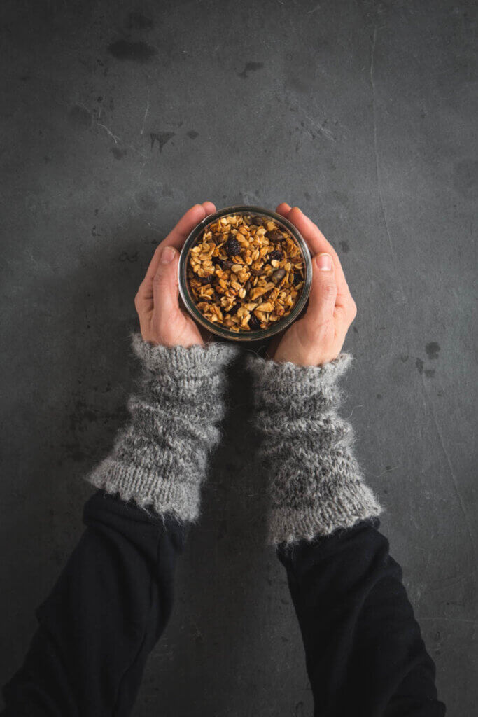 Hände halten Glas mit Knuspermuesli