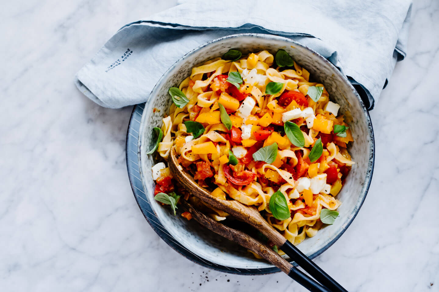 Pasta mit Tomaten-Sugo in Schüssel auf Marmorplatte