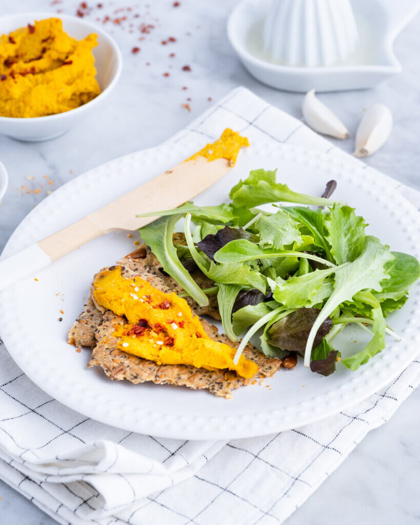 Kürbisaufstrich mit Salat und Cracker auf weißem Teller